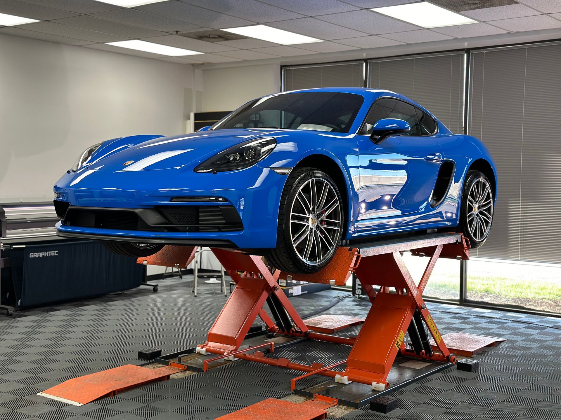 A blue sports car is parked on a lift in a garage.