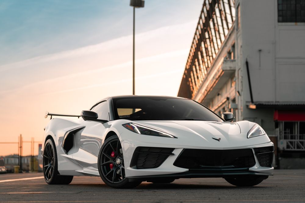 A white corvette is parked in a parking lot in front of a building.