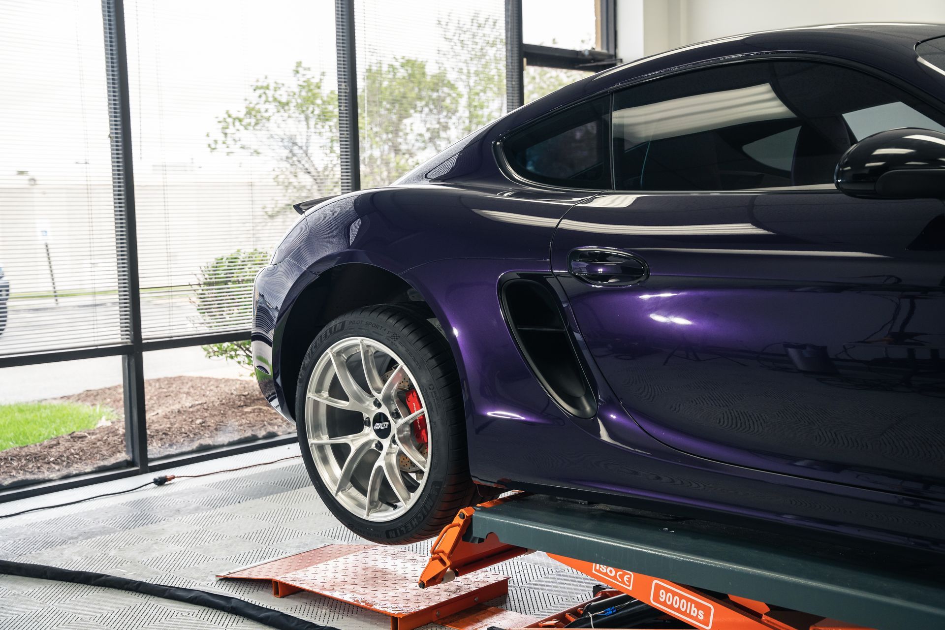 A purple sports car is sitting on a lift in a garage.