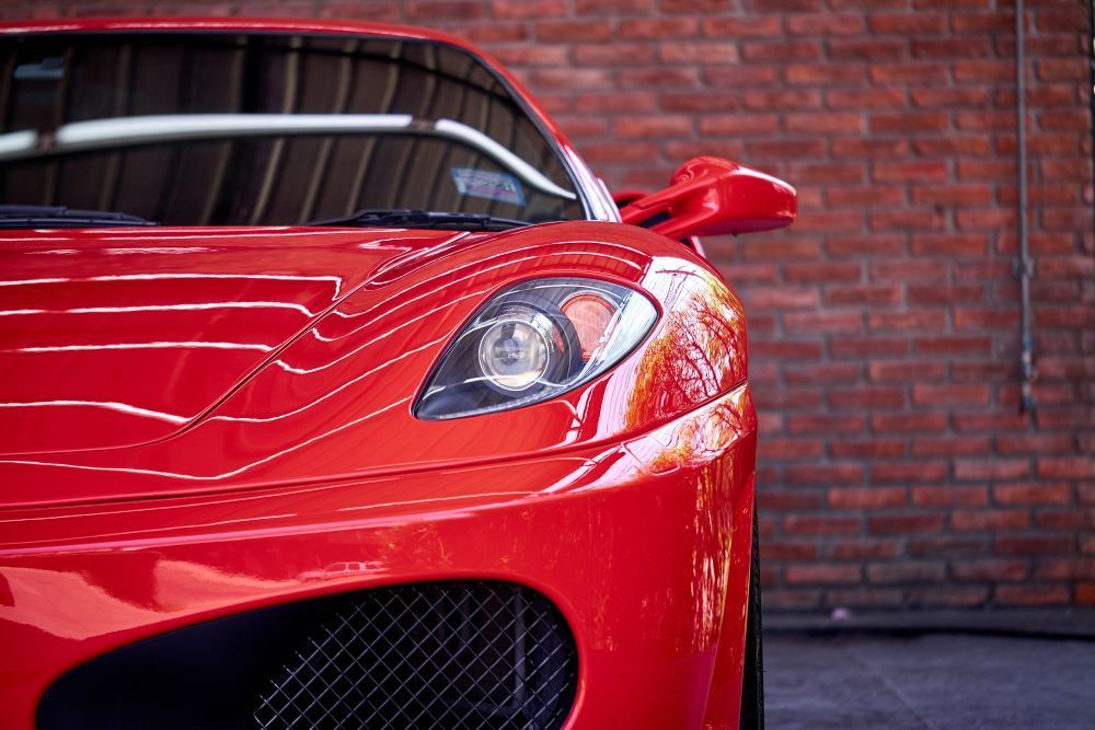A Red Sports Car Is Parked in Front of A Brick Wall — Sell Any Car Fast in North Lakes, QLD