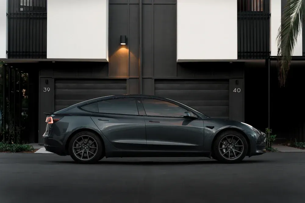 Grey Tesla Model 3 parked in front of an apartment