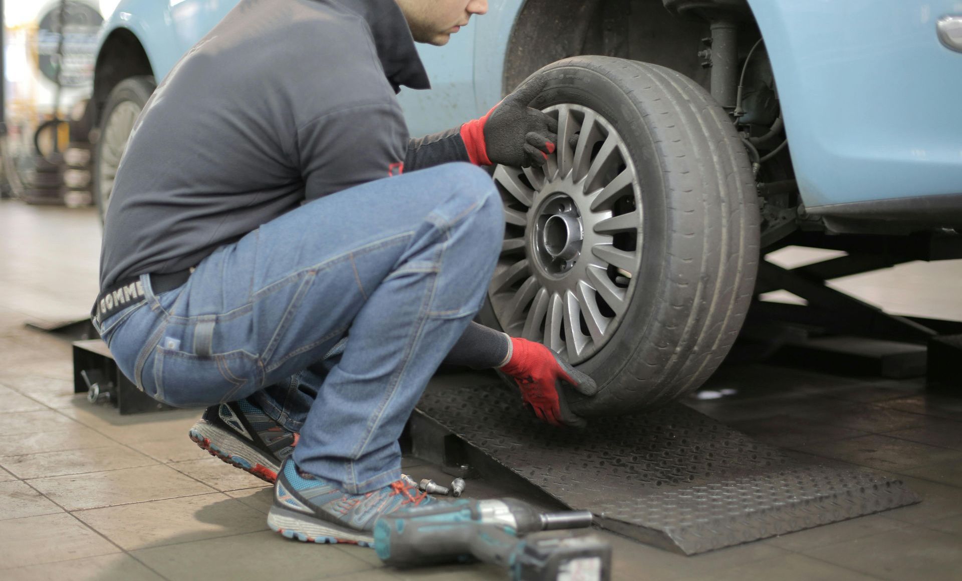 Mechanic changing a tyre on an unroadworthy car thats unregistered