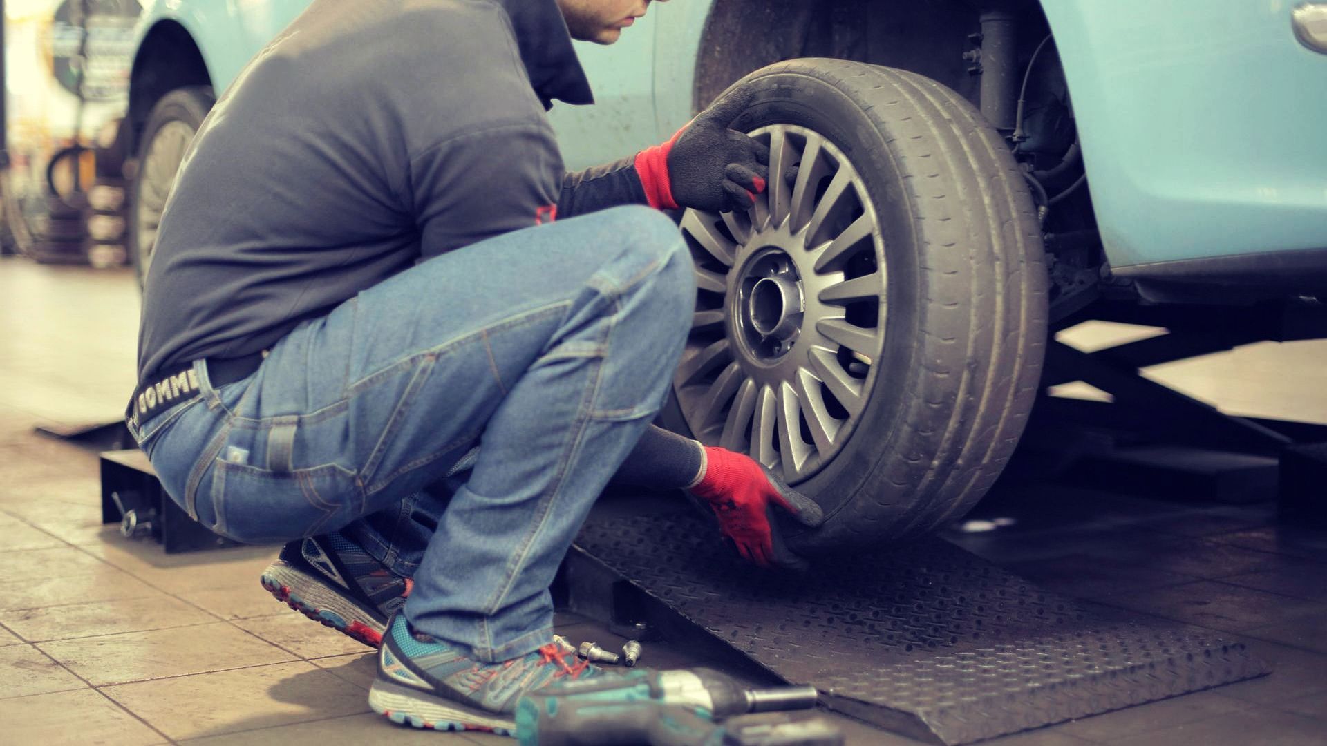 Mechanic changing a tyre on an unroadworthy car thats unregistered