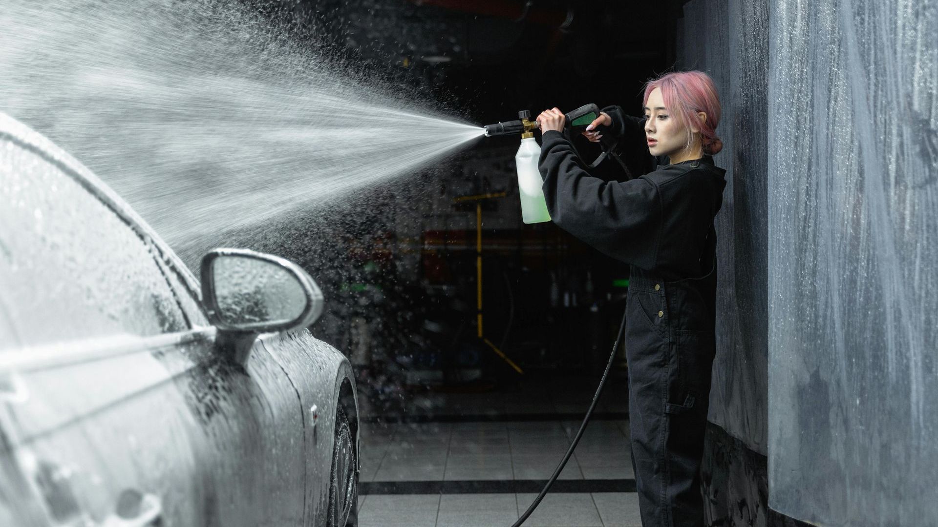 Girl with pink hair washing a car