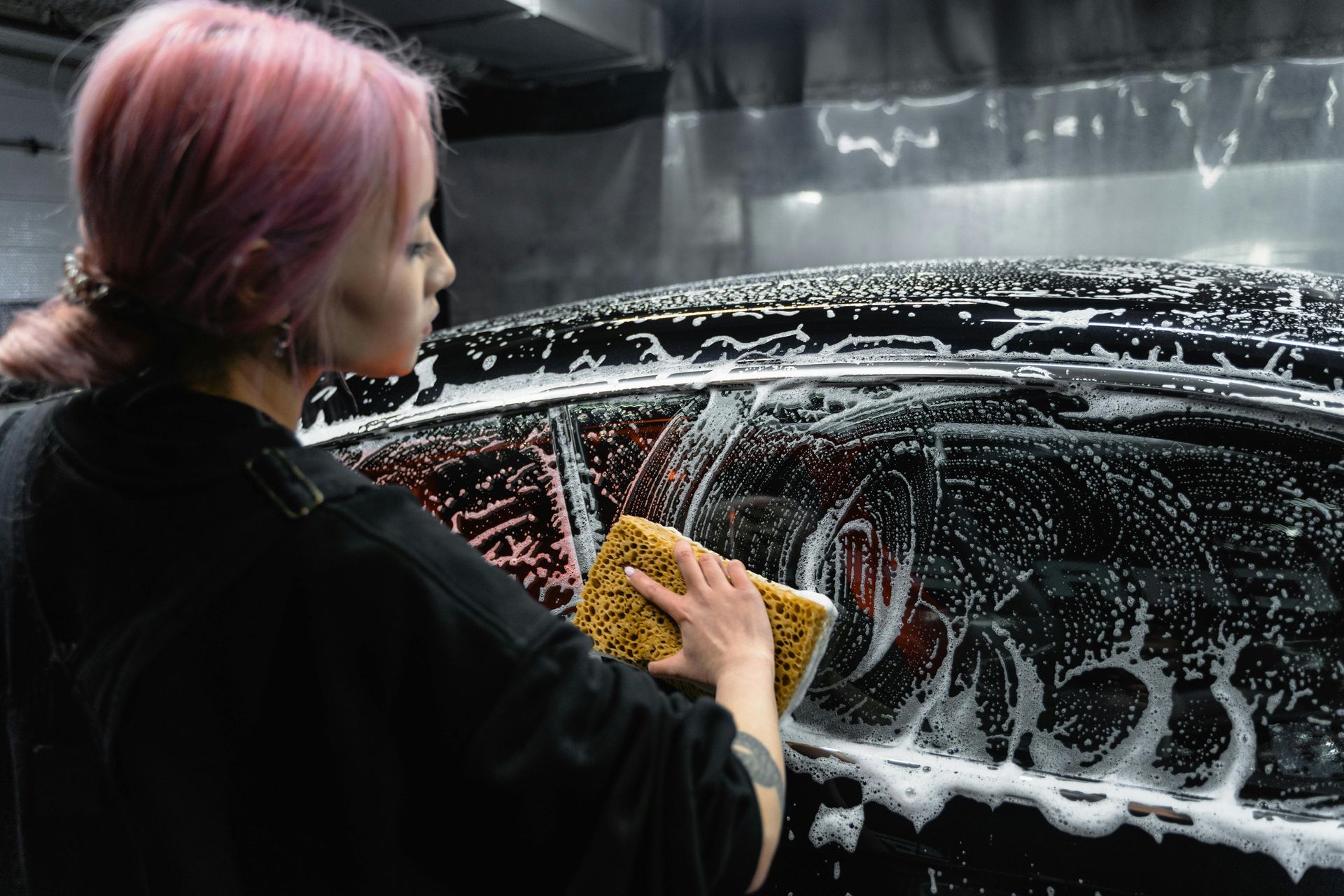 girl with pink hair washing her car