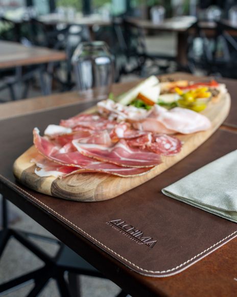 Tagliere di salumi e formaggi su un vassoio di legno. Servito su una tovaglietta marrone, ristorante.