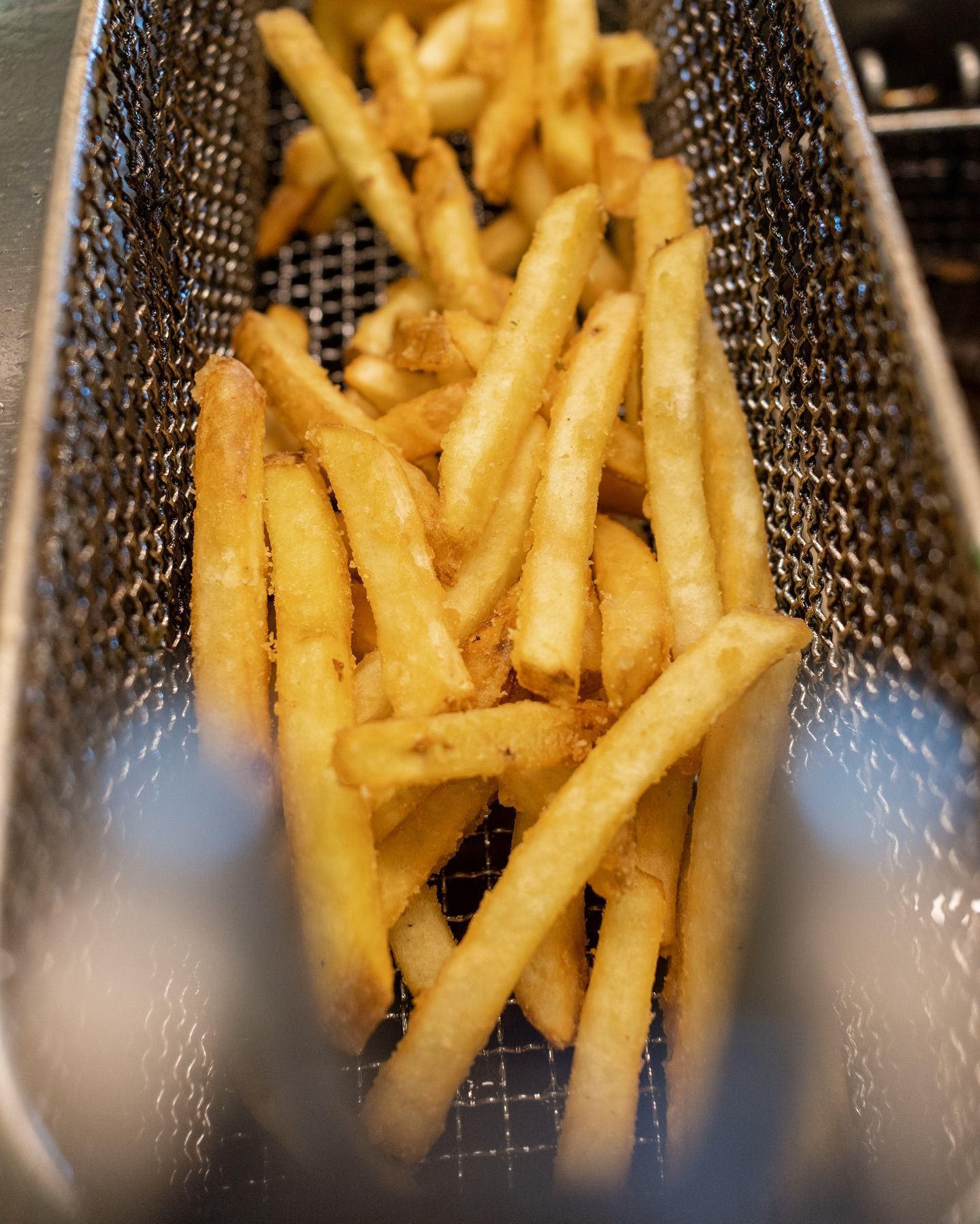Patatine fritte dorate in un cestino di metallo.