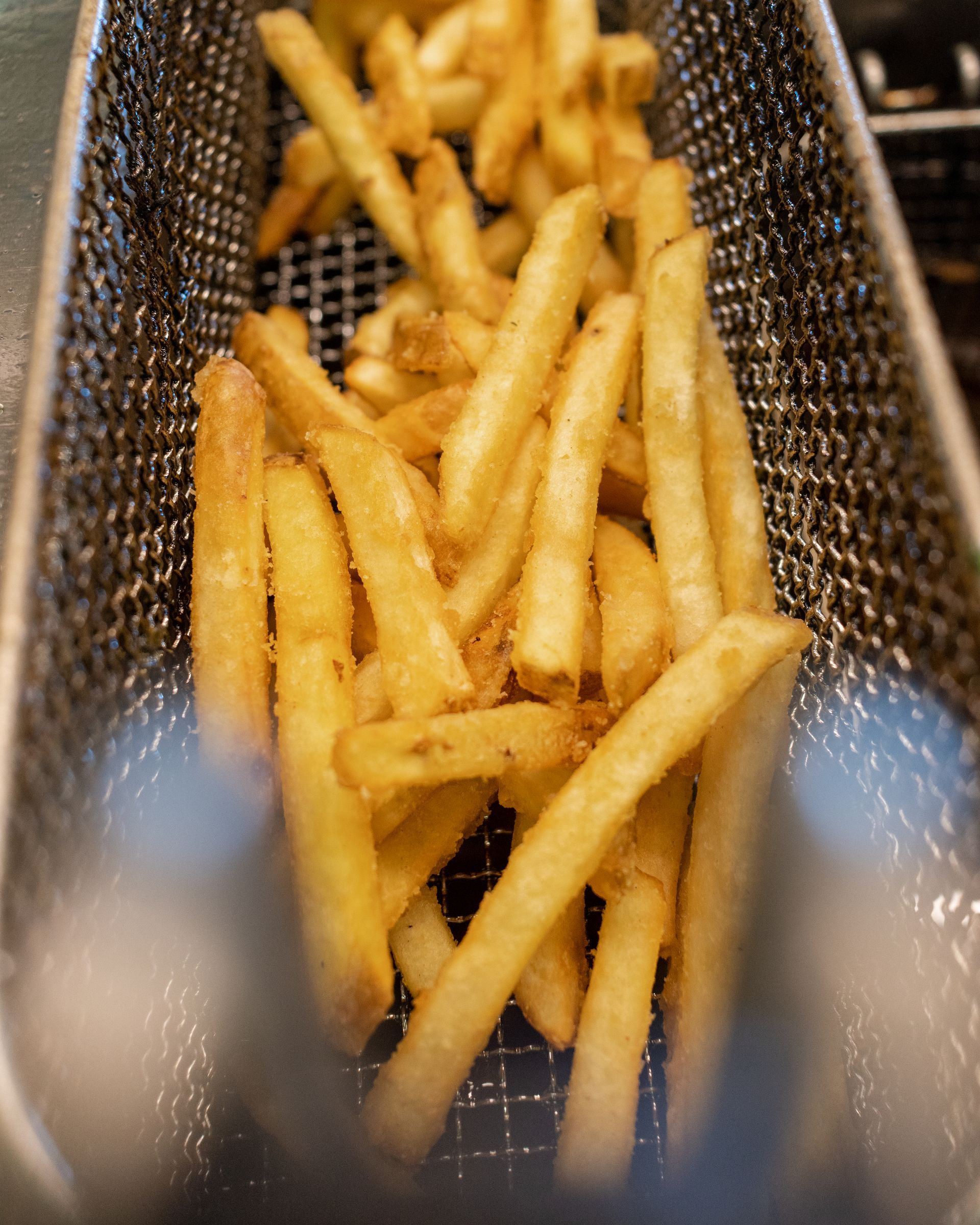 Cocktail e pane piatto con fette d'arancia, guarnito con fiori gialli su un bancone di legno.