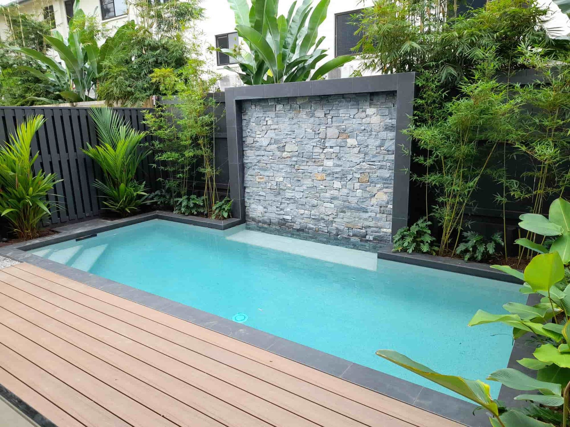 A Small Swimming Pool with A Waterfall in The Backyard — Pools Plus NQ in Kewarra Beach, QLD