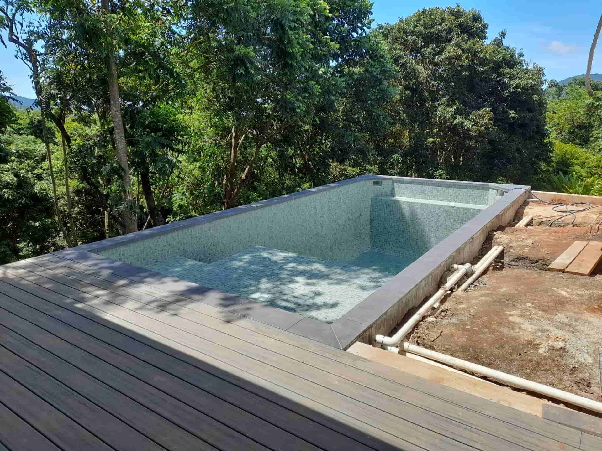 A Large Swimming Pool Is Sitting on Top of A Wooden Deck Surrounded by Trees — Pools Plus NQ in Port Douglas, QLD 