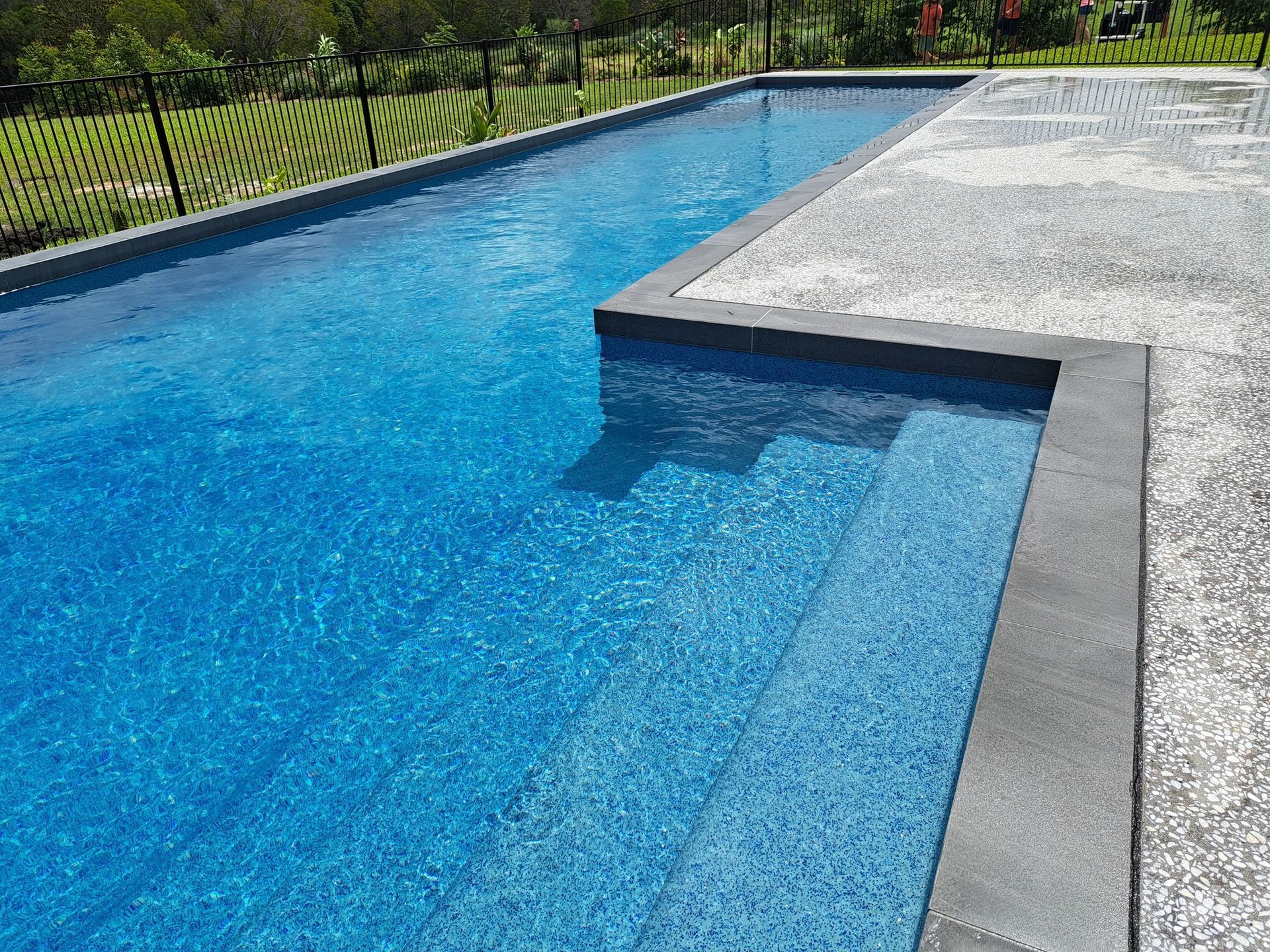 A Large Swimming Pool with Stairs and A House in The Background — Pools Plus NQ in Port Douglas, QLD 