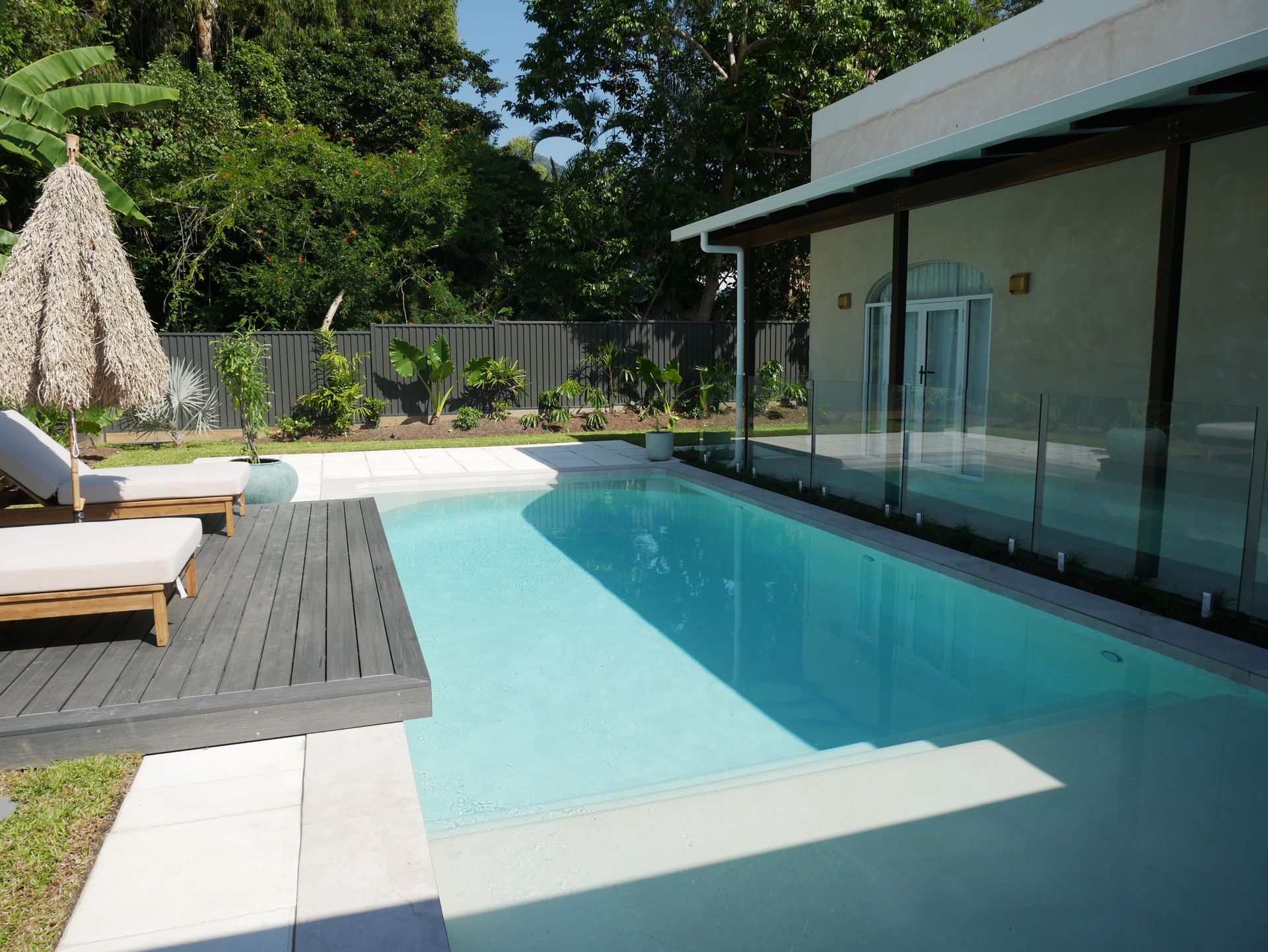A Large Swimming Pool Is Surrounded by A Fence and A Painting on The Wall — Pools Plus NQ in Kewarra Beach, QLD