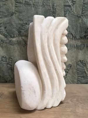 A white sculpture is sitting on top of a wooden table.