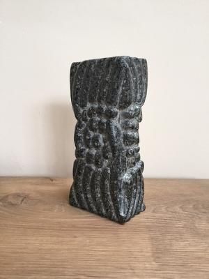 A black vase is sitting on top of a wooden table.