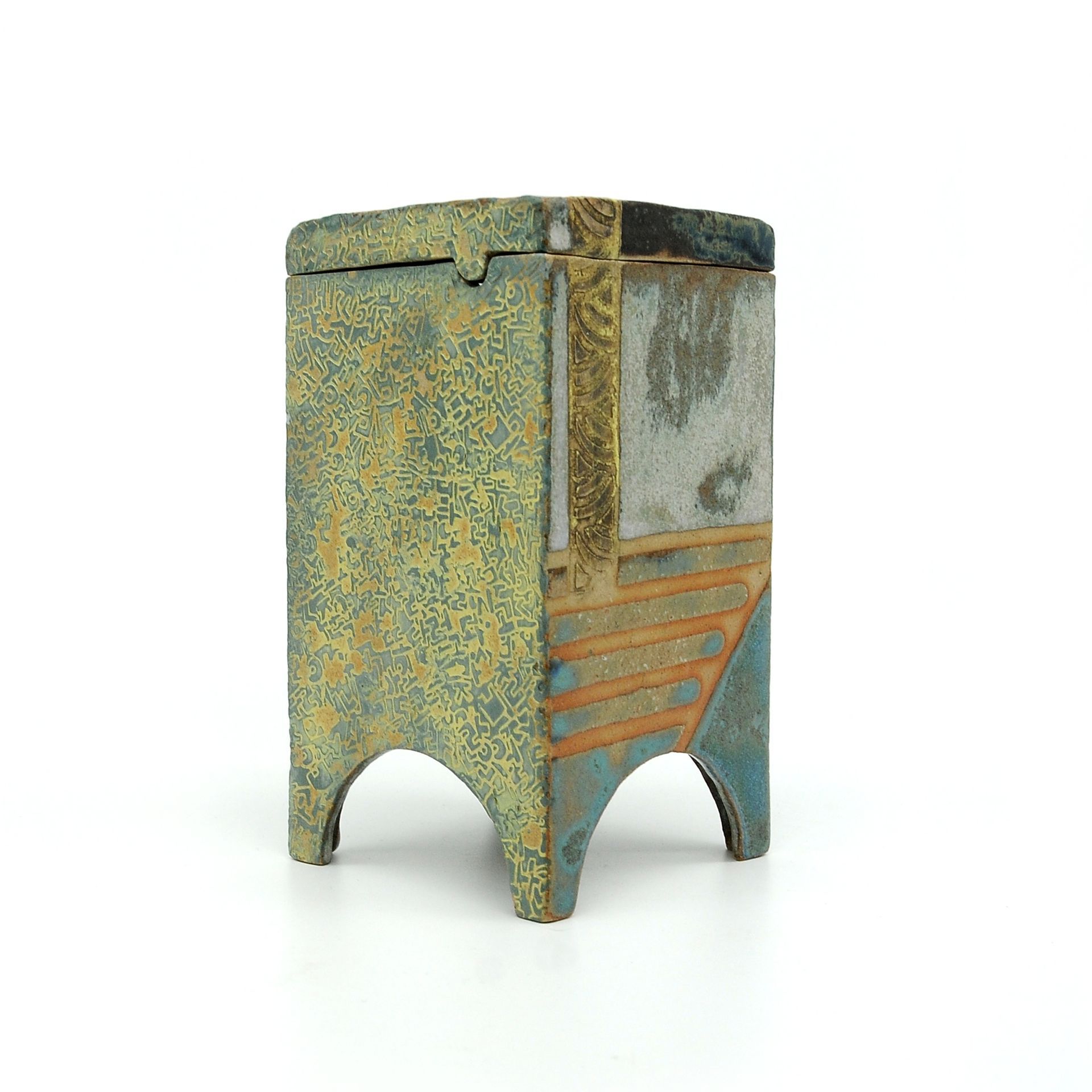 a small ceramic vase with a lid is sitting on a white surface .