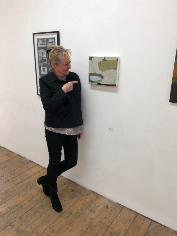 A woman is pointing at a painting on a wall
