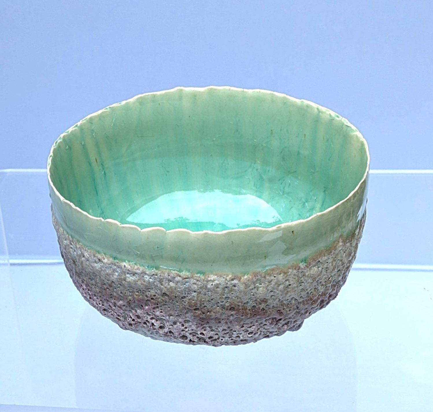 A green bowl is sitting on a glass shelf