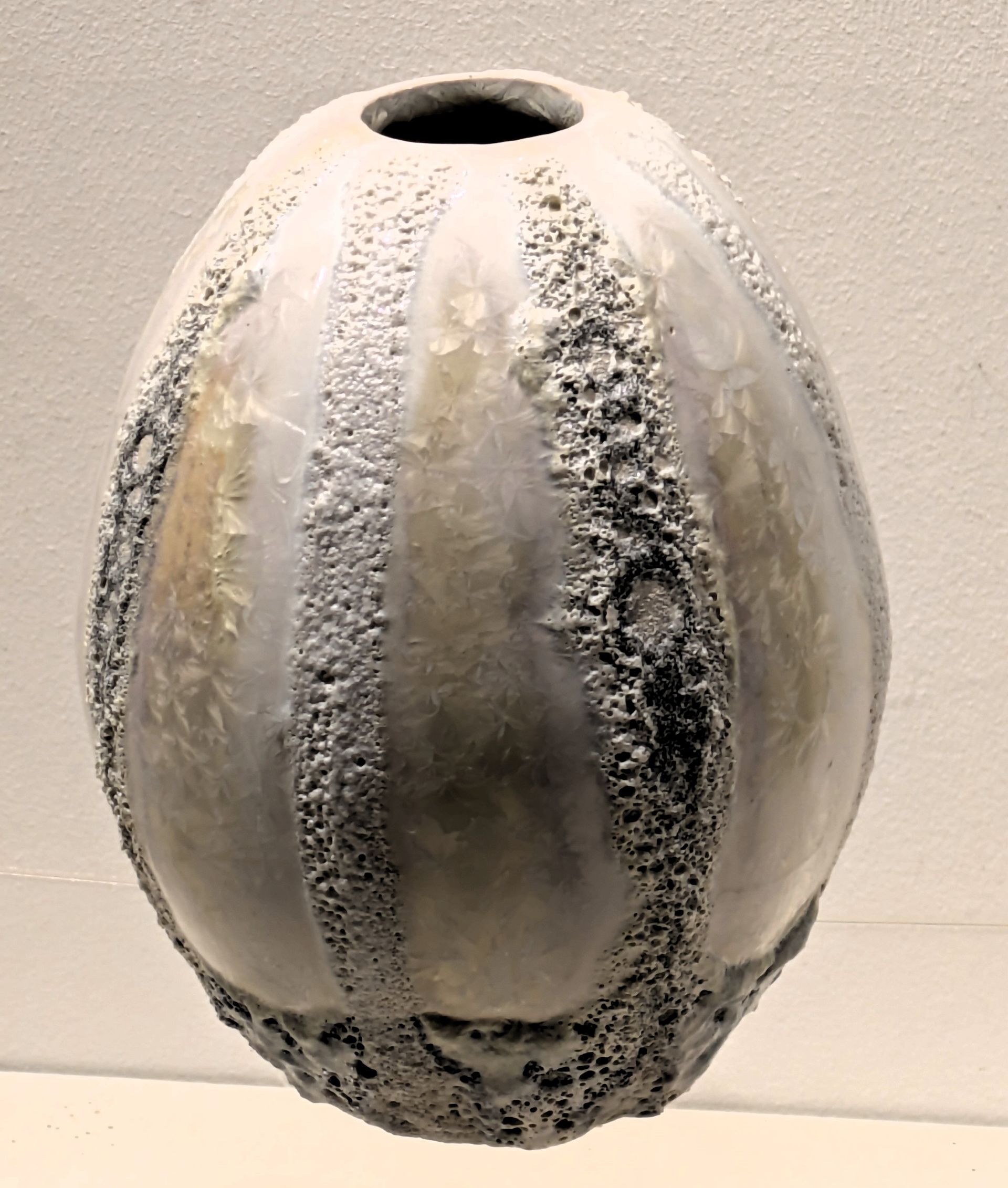 A white vase with a hole in the middle is sitting on a table.