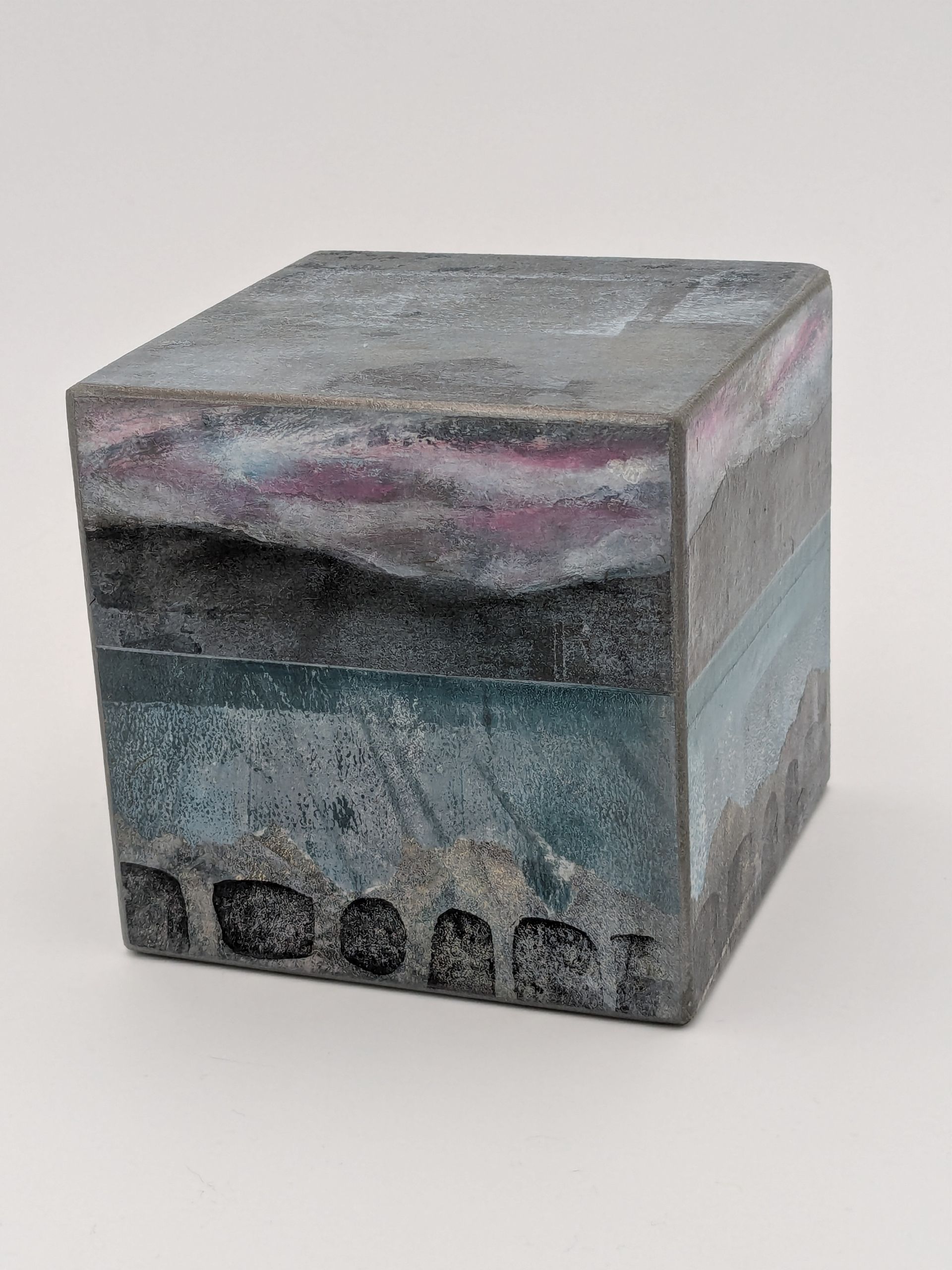 A cube with a painting on it is sitting on a table.