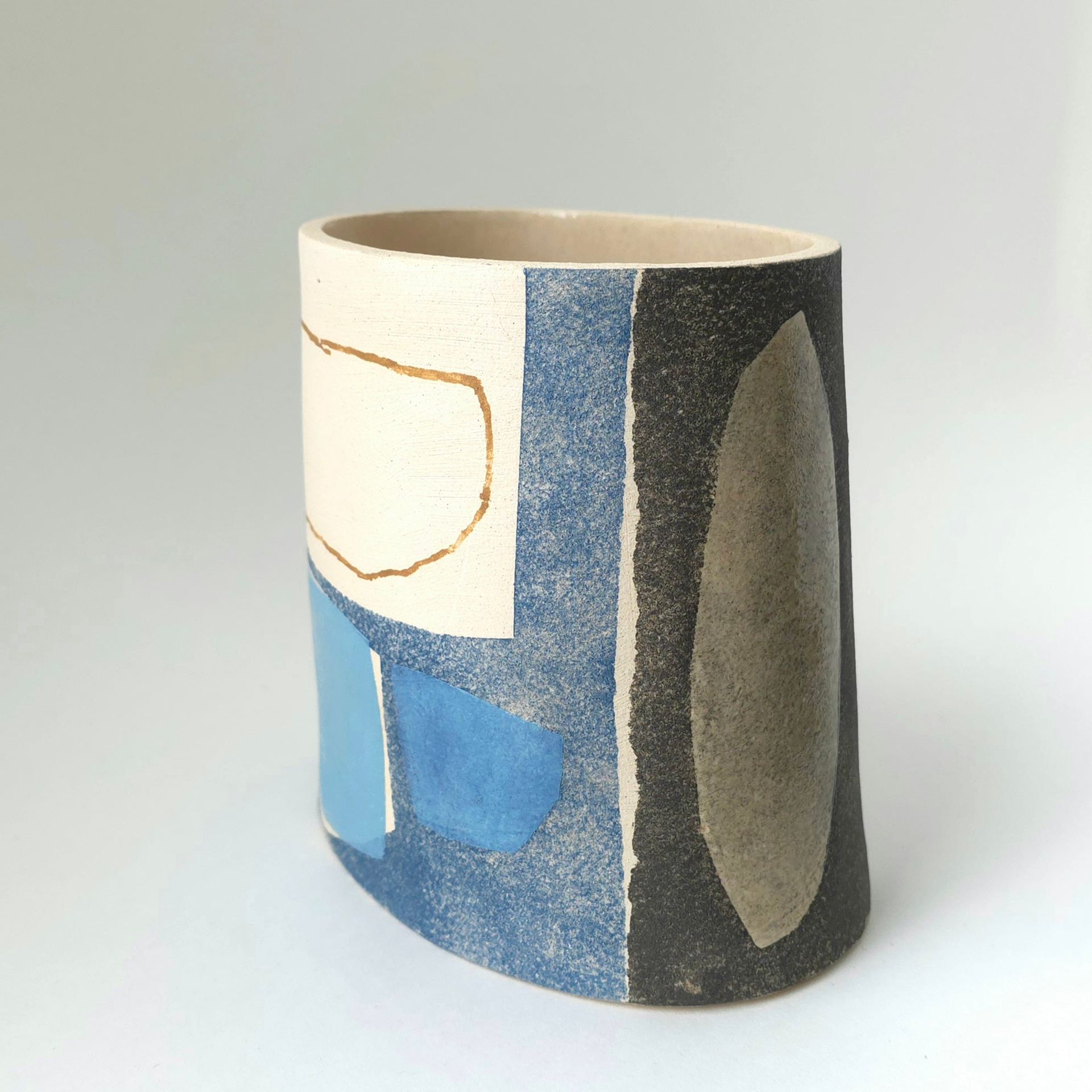 A ceramic vase with a blue and black design on it