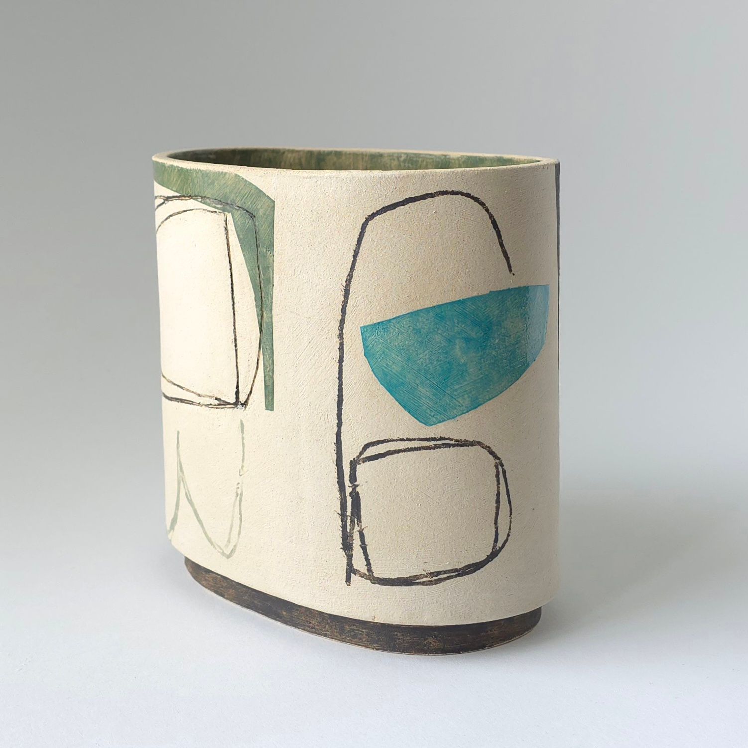 Oval ceramic vase with a speckled cream surface, featuring dark hand-drawn outlines and geometric teal and green shapes.