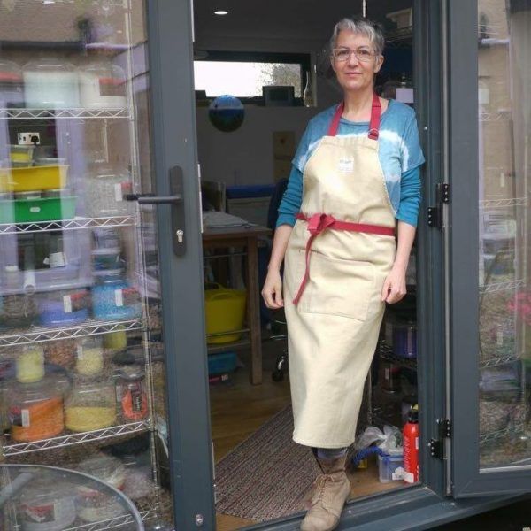 A woman in an apron is standing in a doorway