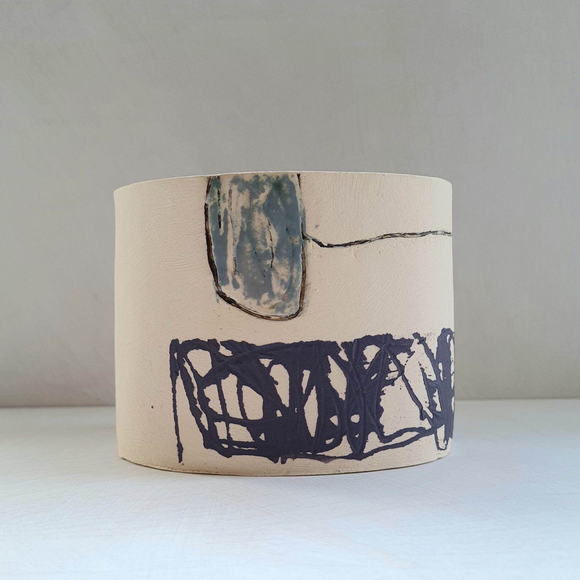 a white ceramic vessel with a blue and black design on it