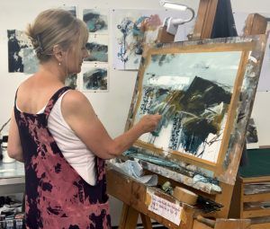 A woman is painting a picture on an easel.