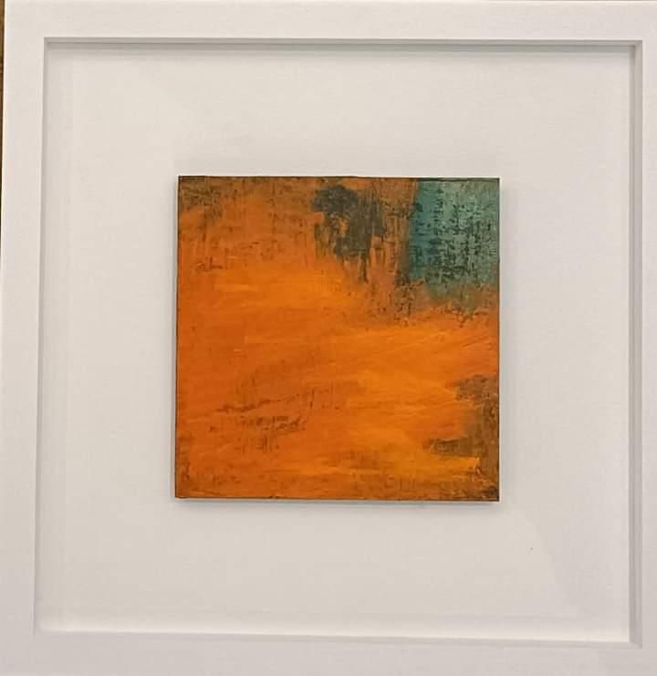 a painting in a white frame is hanging on a wall .