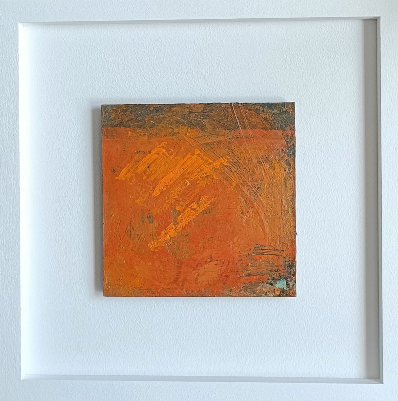 a small orange painting in a white frame