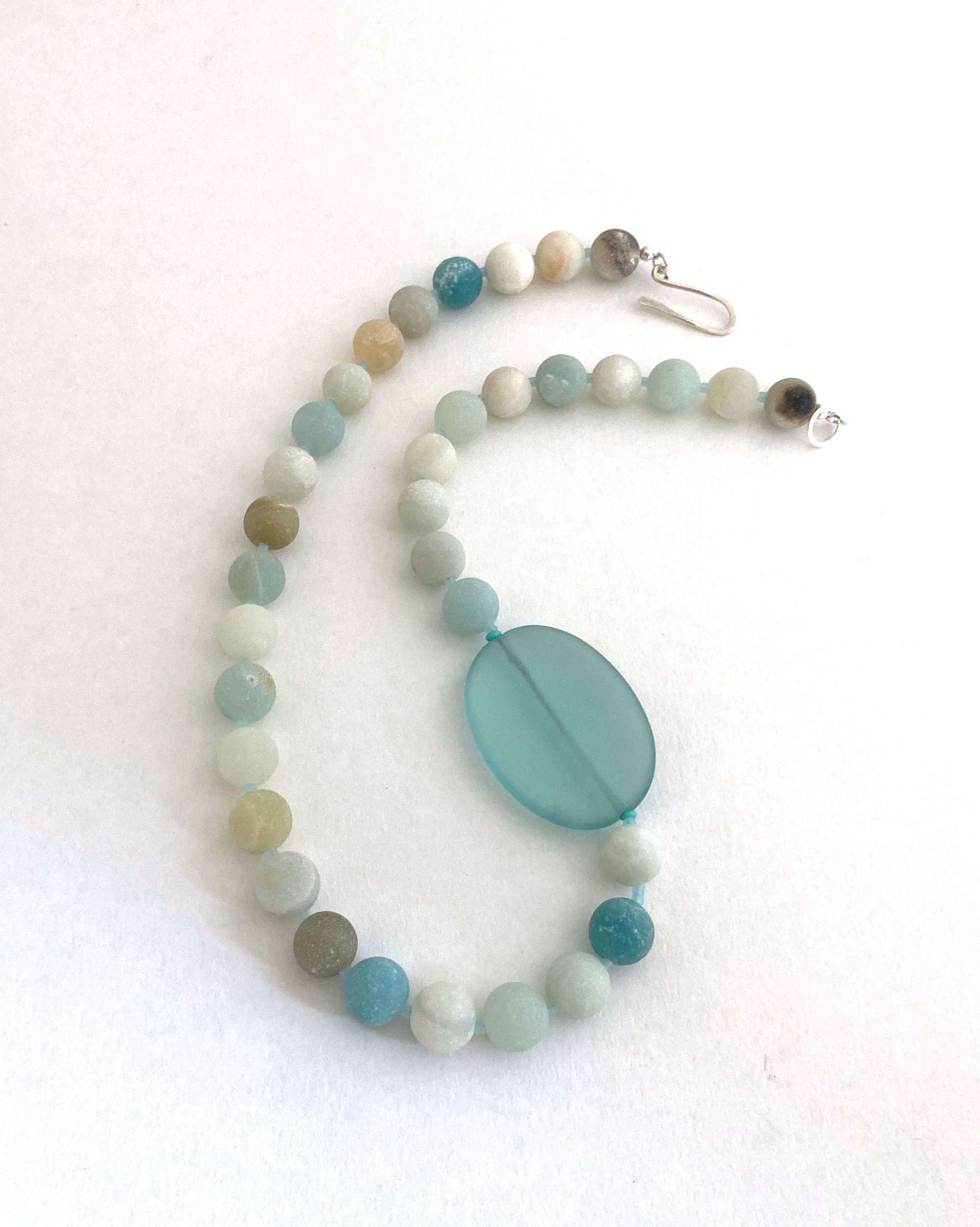 A necklace with pink beads and a square with the letter b on it