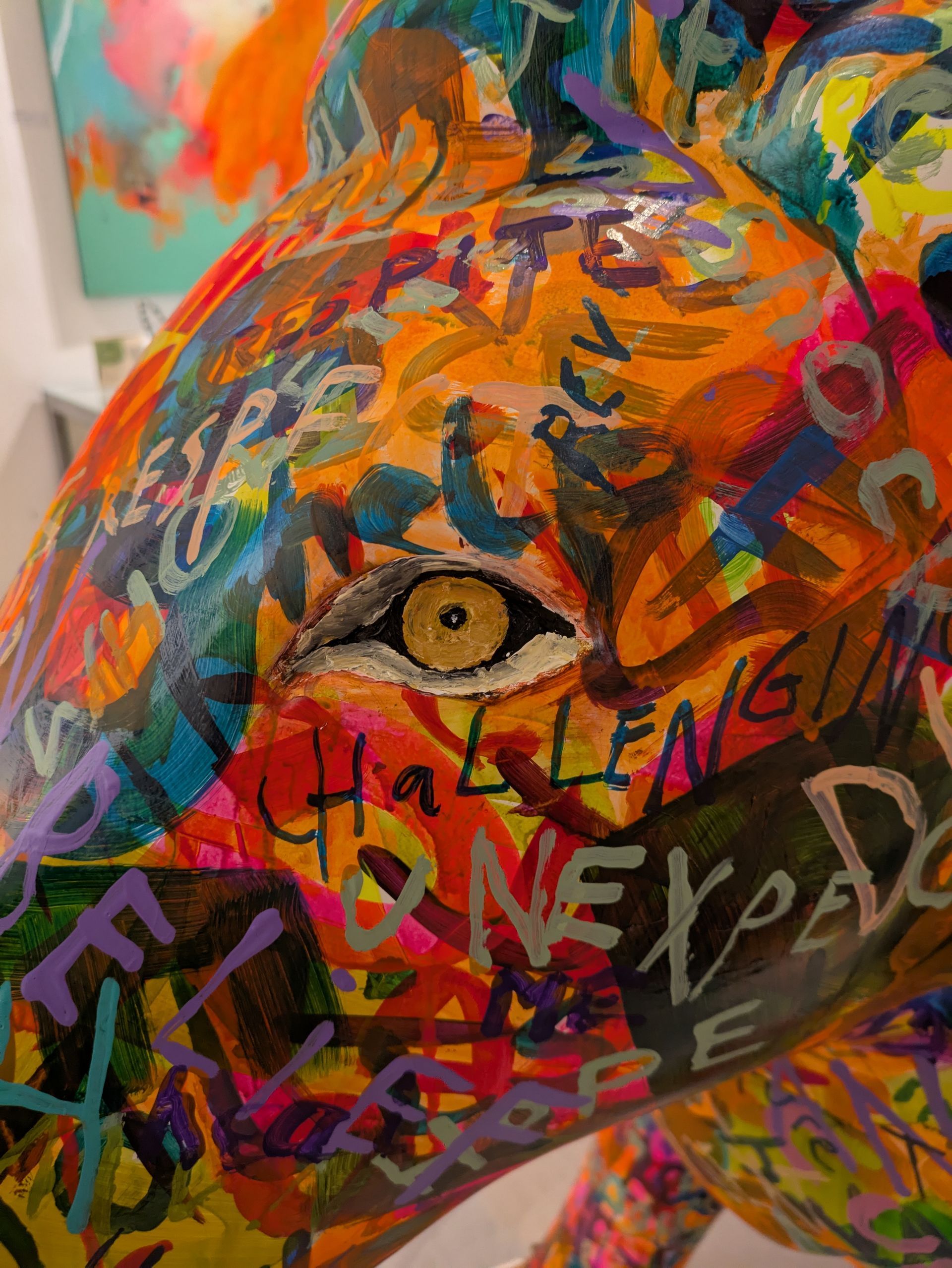 A close up of a colorful painting of a giraffe 's face.