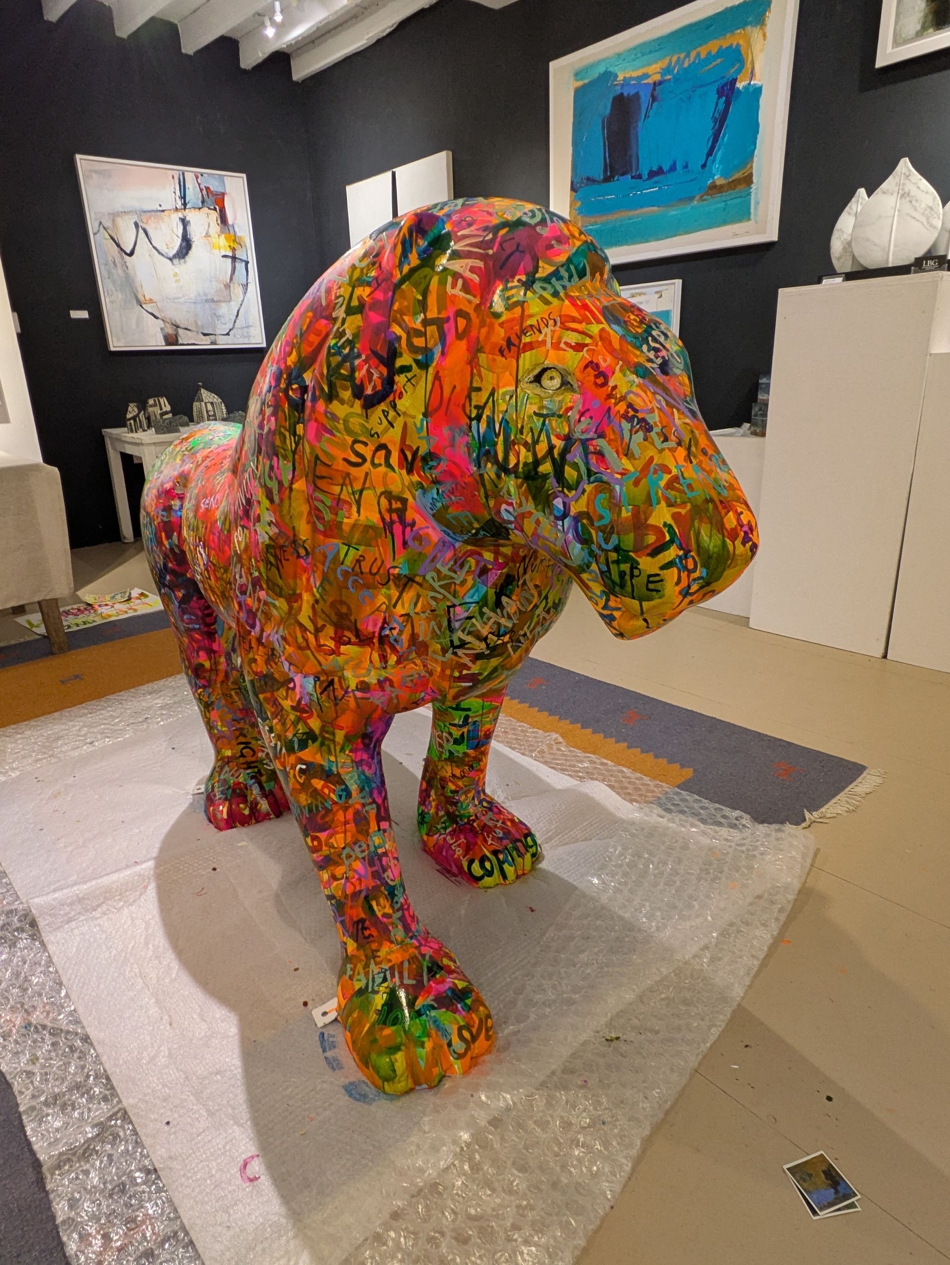 A colorful statue of a lion is sitting on a rug in a room.