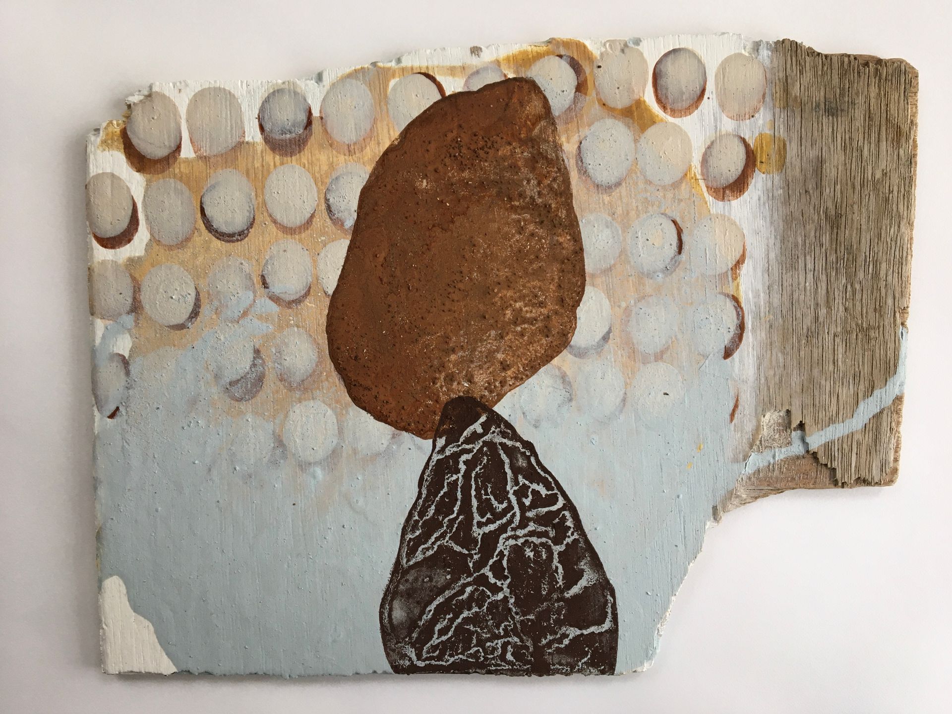 Abstract artwork with a brown oval above a dark patterned shape on a pale, textured background