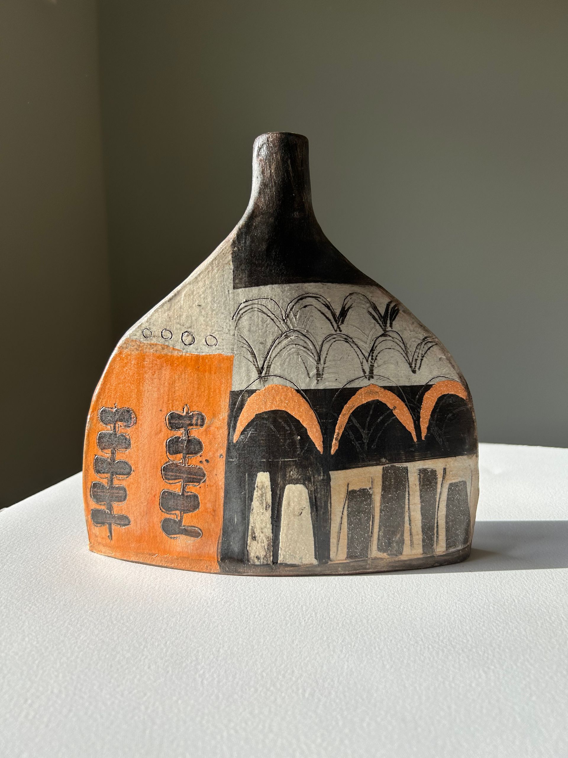 A small ceramic vase is sitting on a white table.
