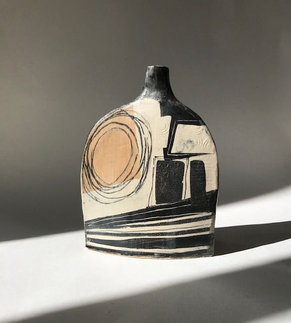 A black and white vase with a geometric design is sitting on a table.