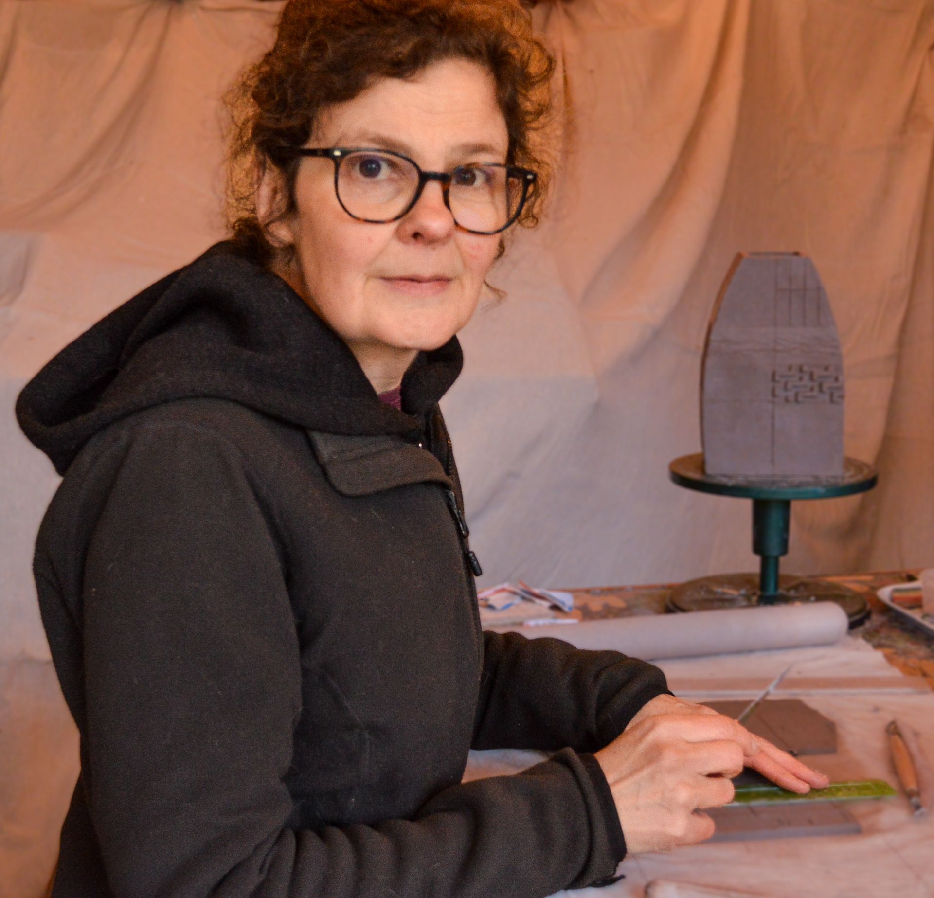 A woman is sitting at a table painting with a brush.