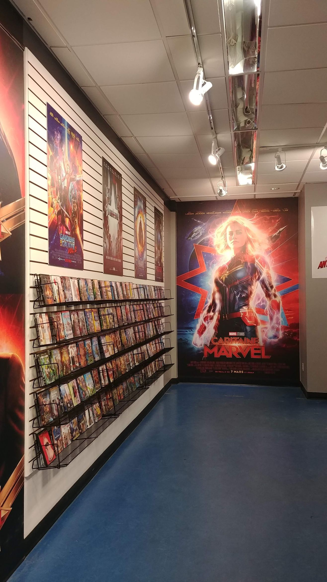 A room with a lot of posters on the wall and a poster of captain marvel on the wall.