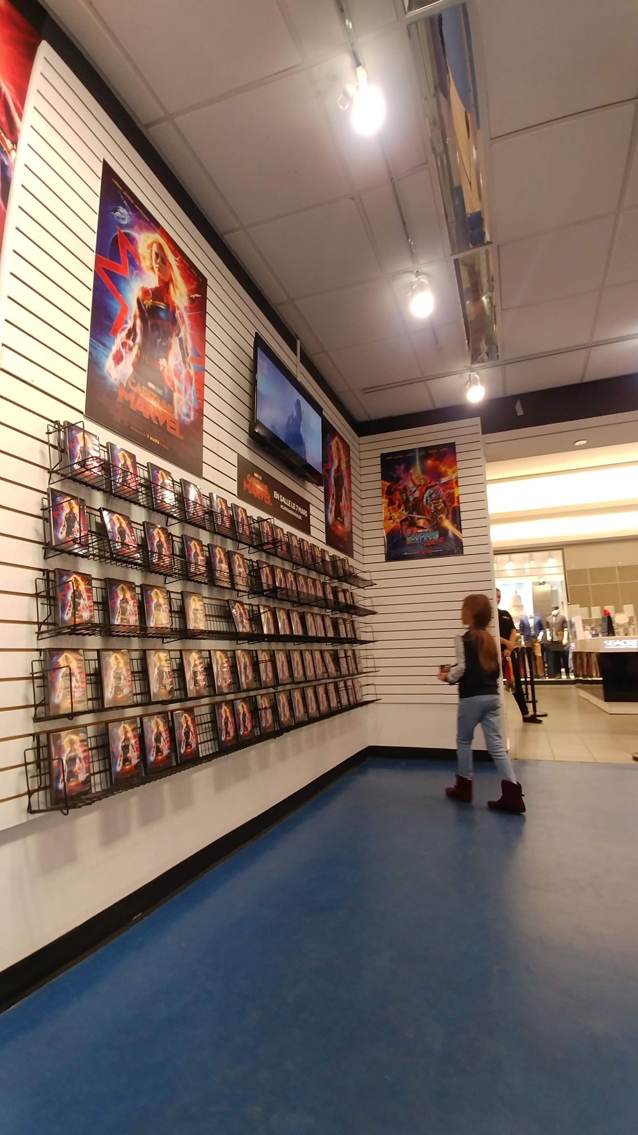 A woman is standing in front of a wall of dvds in a store.
