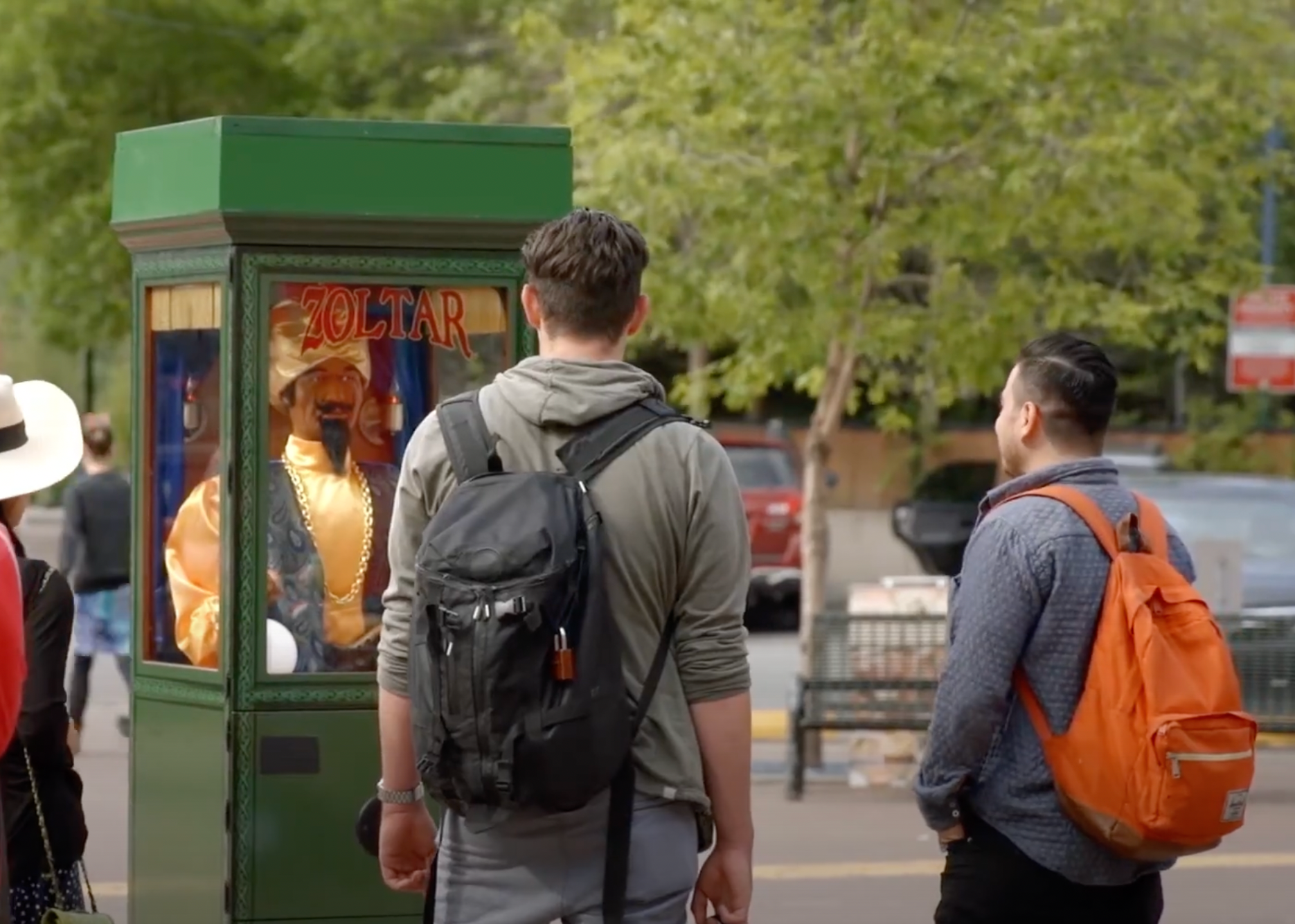 Two men with backpacks are standing in front of a green booth.
