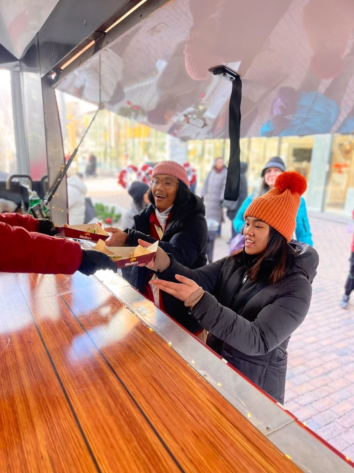 A woman is serving food to another woman at a food truck.