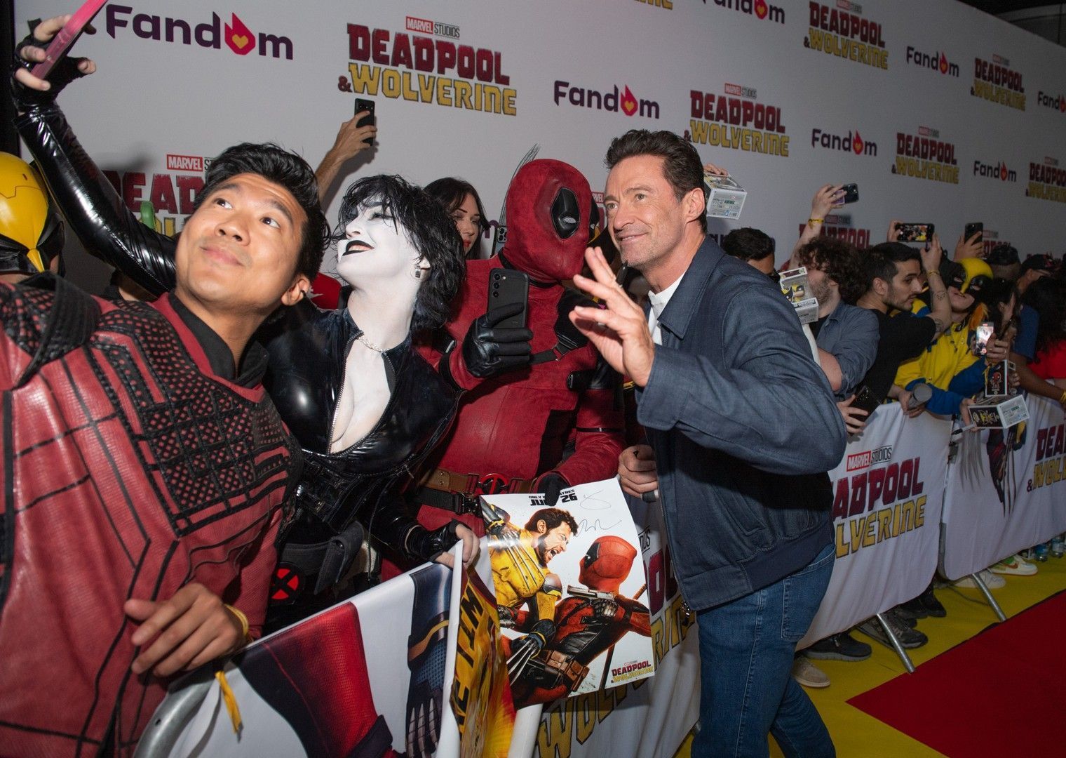 A man in a deadpool costume is taking a selfie with a fan