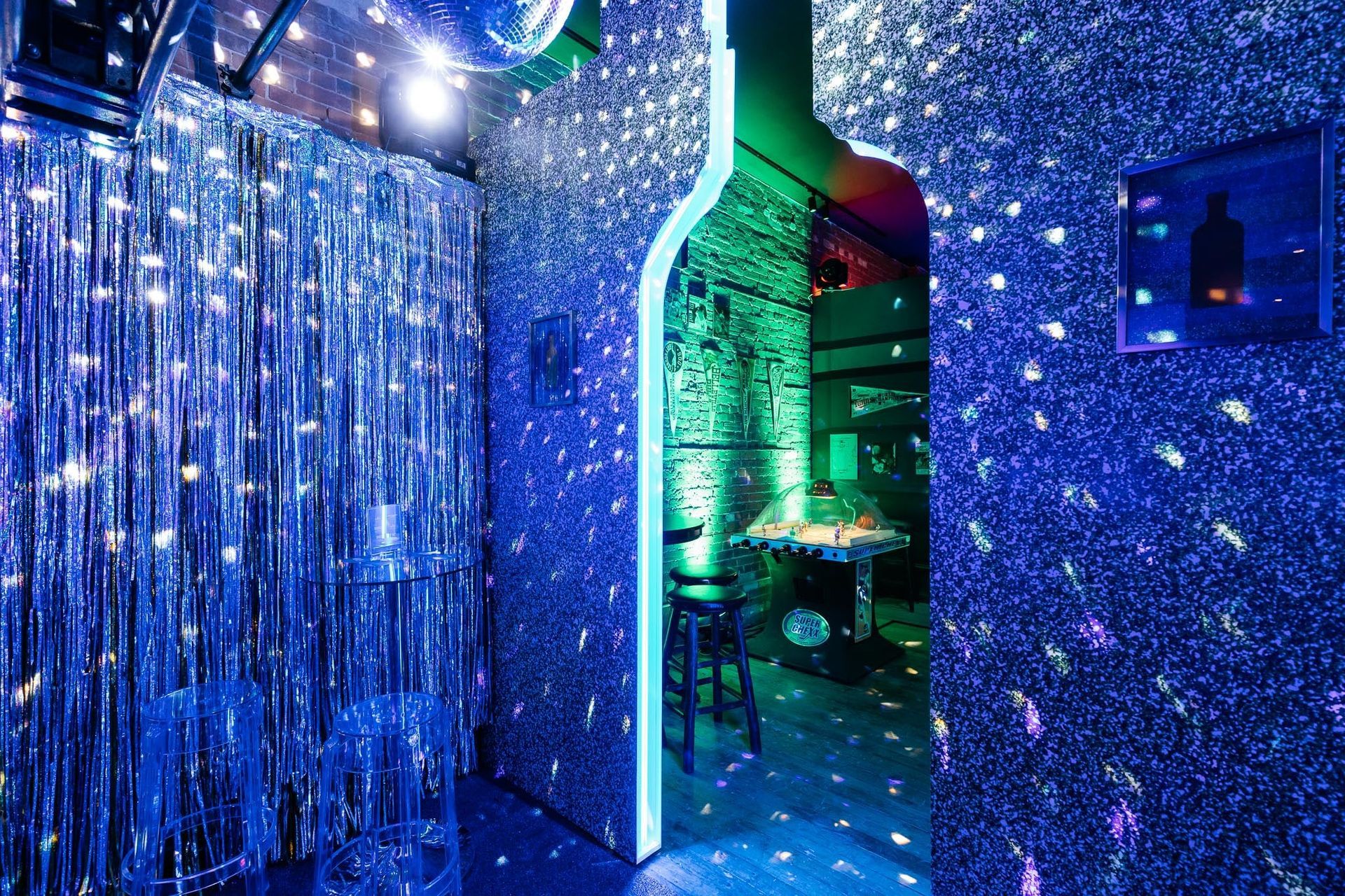 A room with a bottle in the middle of it and a disco ball on the wall.