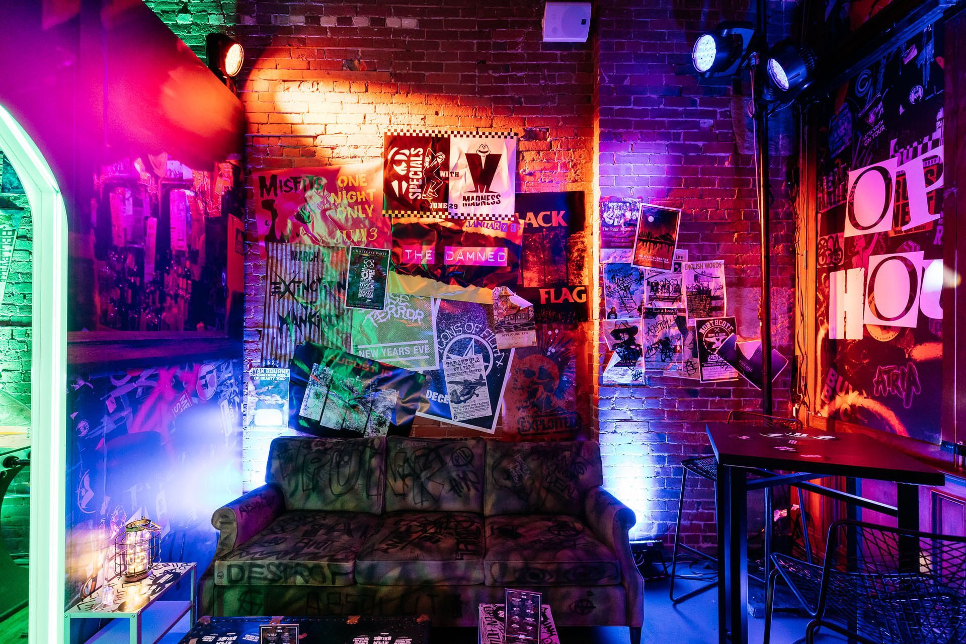 A room with a couch , table , and neon lights.