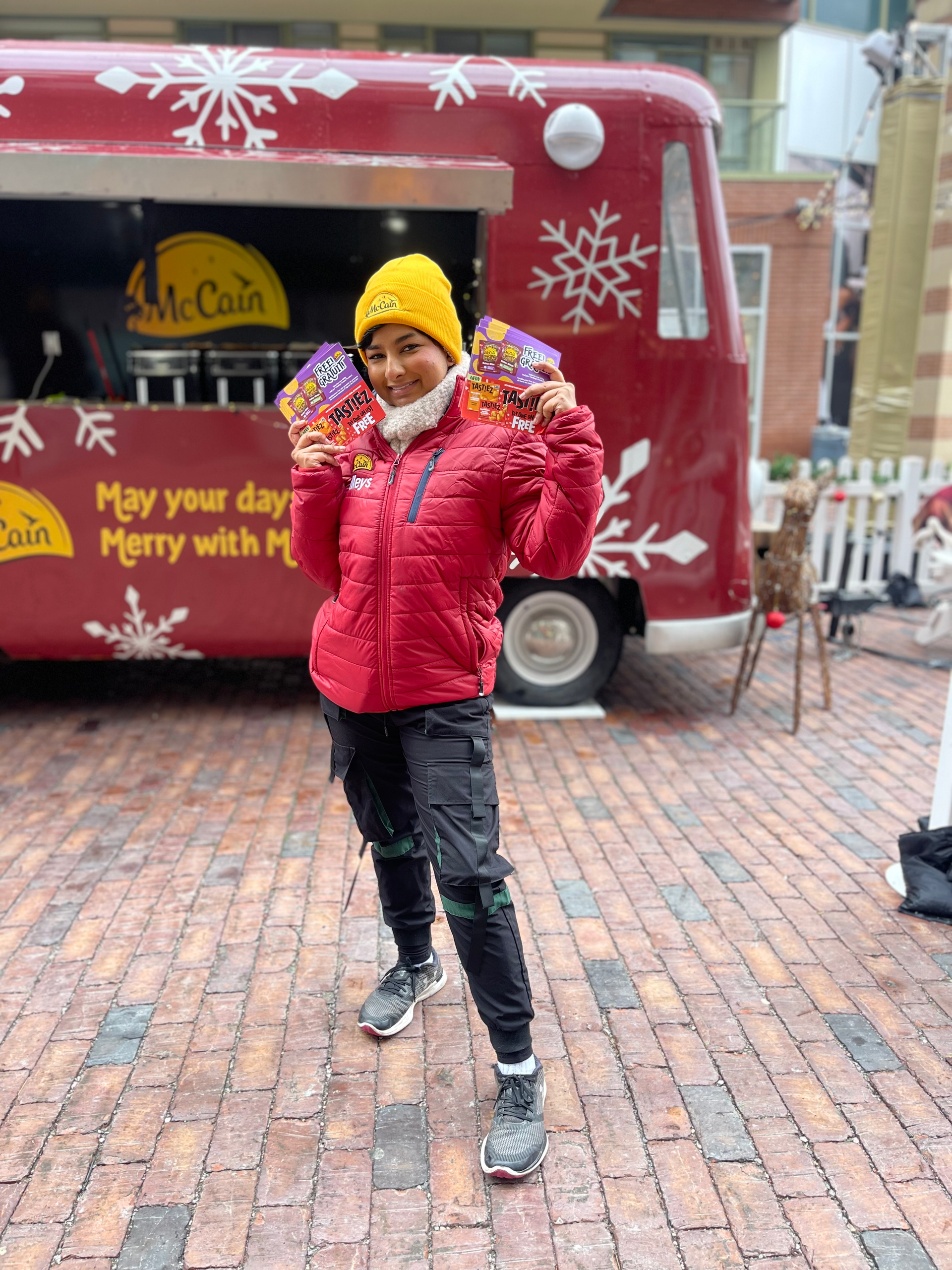 A woman is standing in front of a red food truck holding candy.