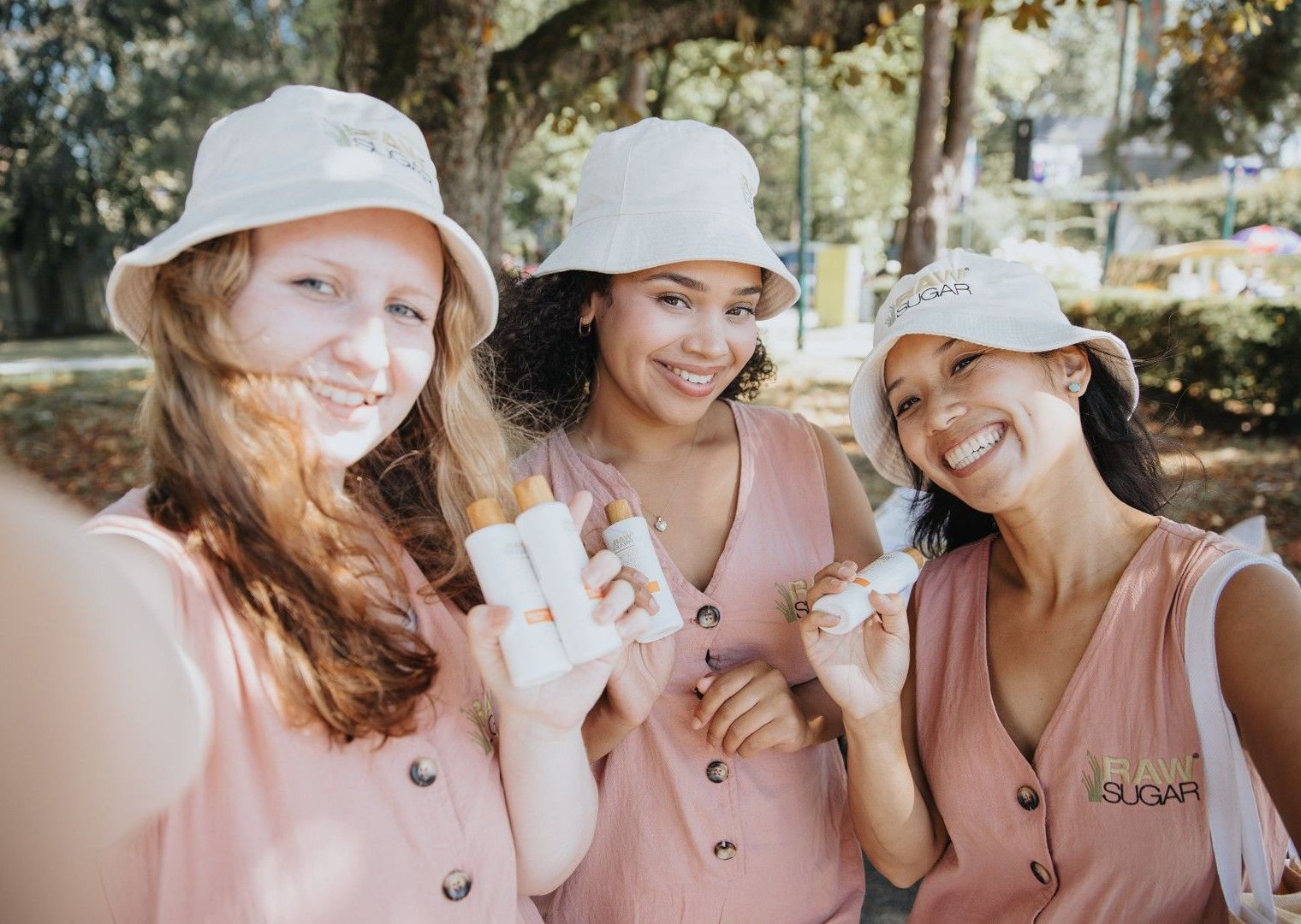 Three young women are taking a selfie in a park while holding ice cream cones.