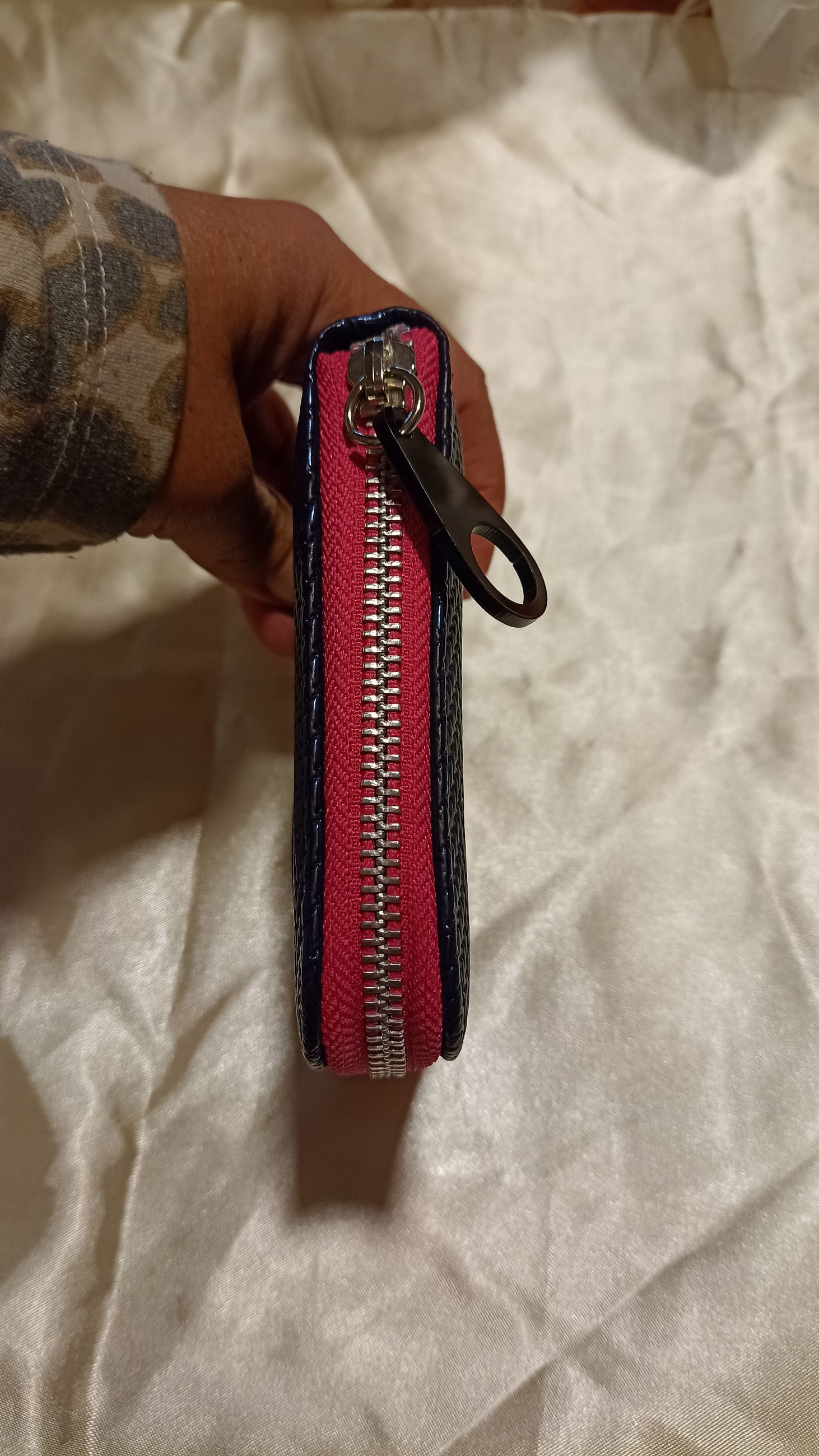 Cartera azul brillante con cremallera circundante y etiqueta 