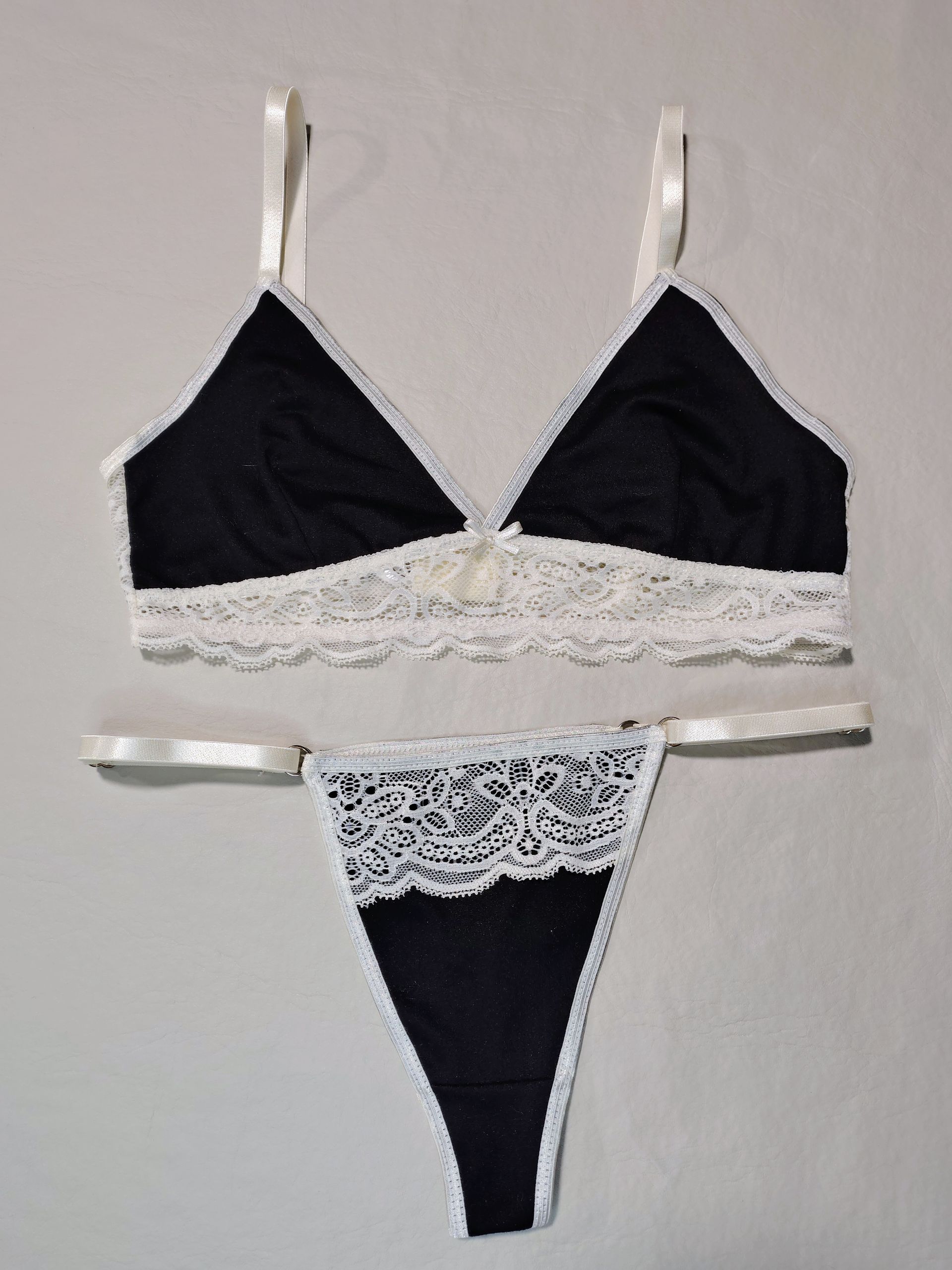 Conjunto de lencería en blanco y negro con sujetador triangular y tanga, adornado con encaje.