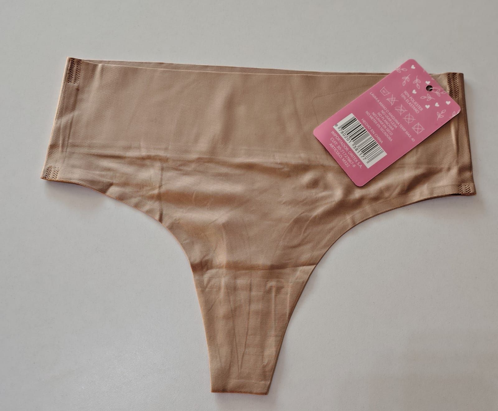 Ropa interior tipo tanga de color canela con etiqueta rosa adherida, sobre una superficie blanca.