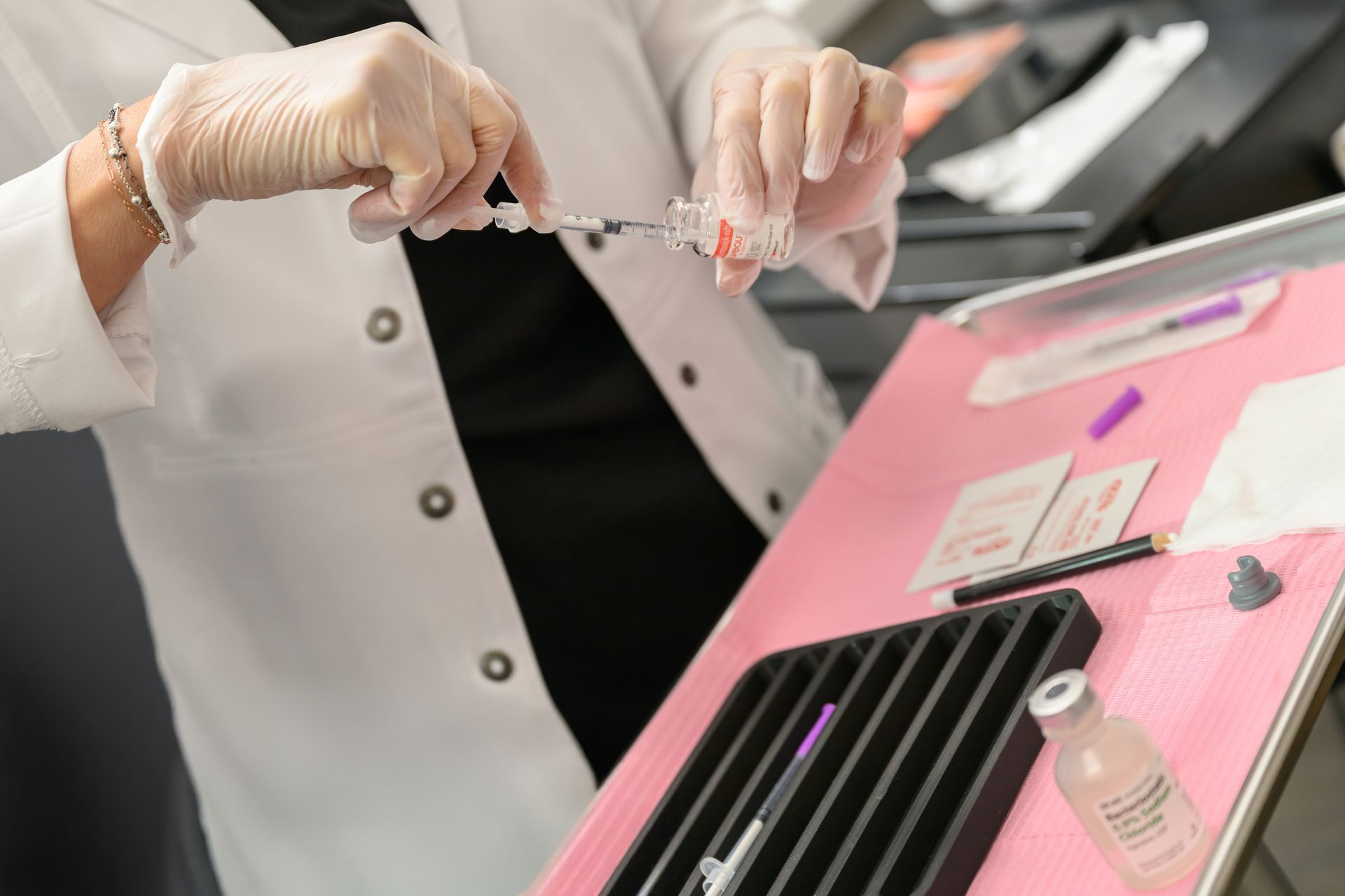A woman in a lab coat is holding a syringe in her hand.